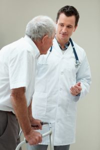 Handsome doctor assisting an old man on a walker